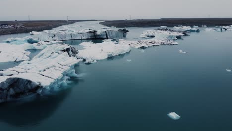 drone shot of beatiful black and white icebergs floating in a blue lagoon in iceland near the ring road