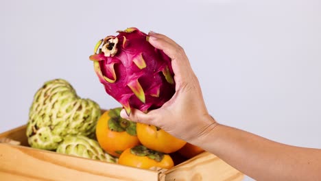 hand picking dragon fruit from fruit basket