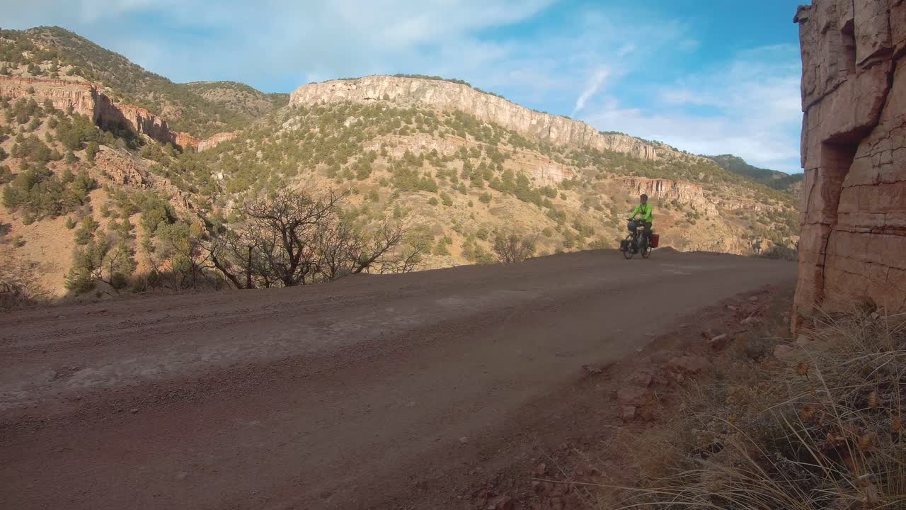 Uomo in bikepacking su una strada sterrata di montagna in Colorado, inquadratura fissa.