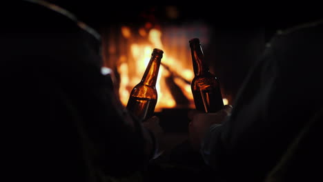 amigos beben cerveza sentados junto a la chimenea vista trasera