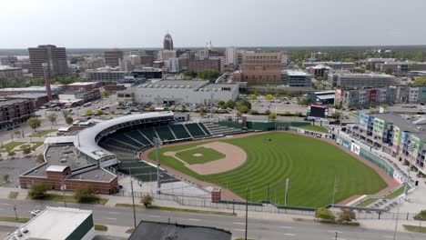 Wide-shot-of-Lansing,-Michigan-skyline-and-minor-league-baseball-stadium-with-drone-video-moving-in