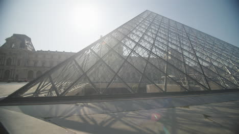 Panning-left-outside-famous-glass-pyramid-of-the-Louvre-in-Paris,-France