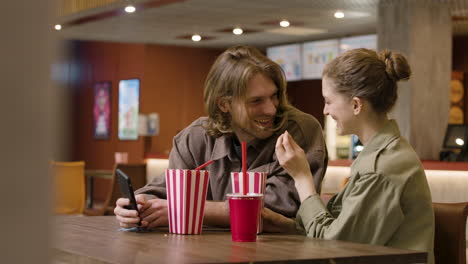 una pareja feliz divirtiéndose juntos mientras comían palomitas de maíz en el snack bar del cine