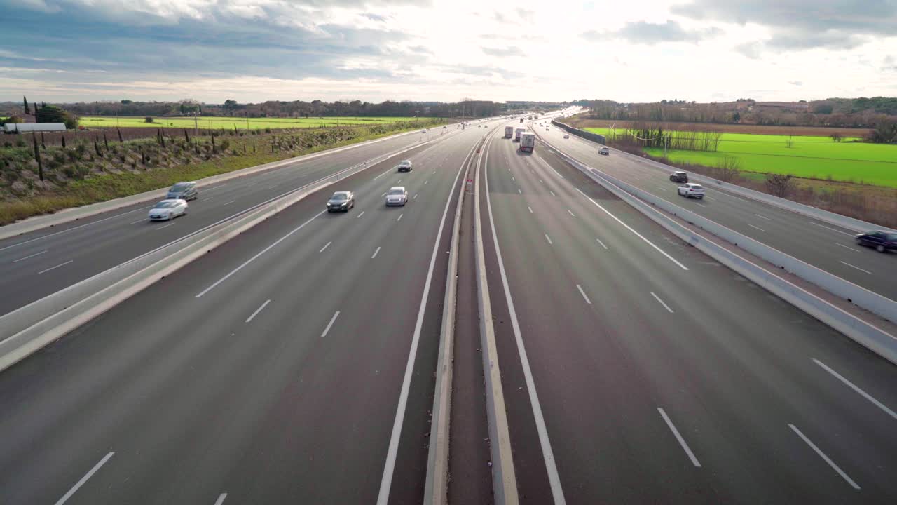 Looking at cars passing by on a quiet highway from above, smooth panning to the horizon with blue sky and clouds