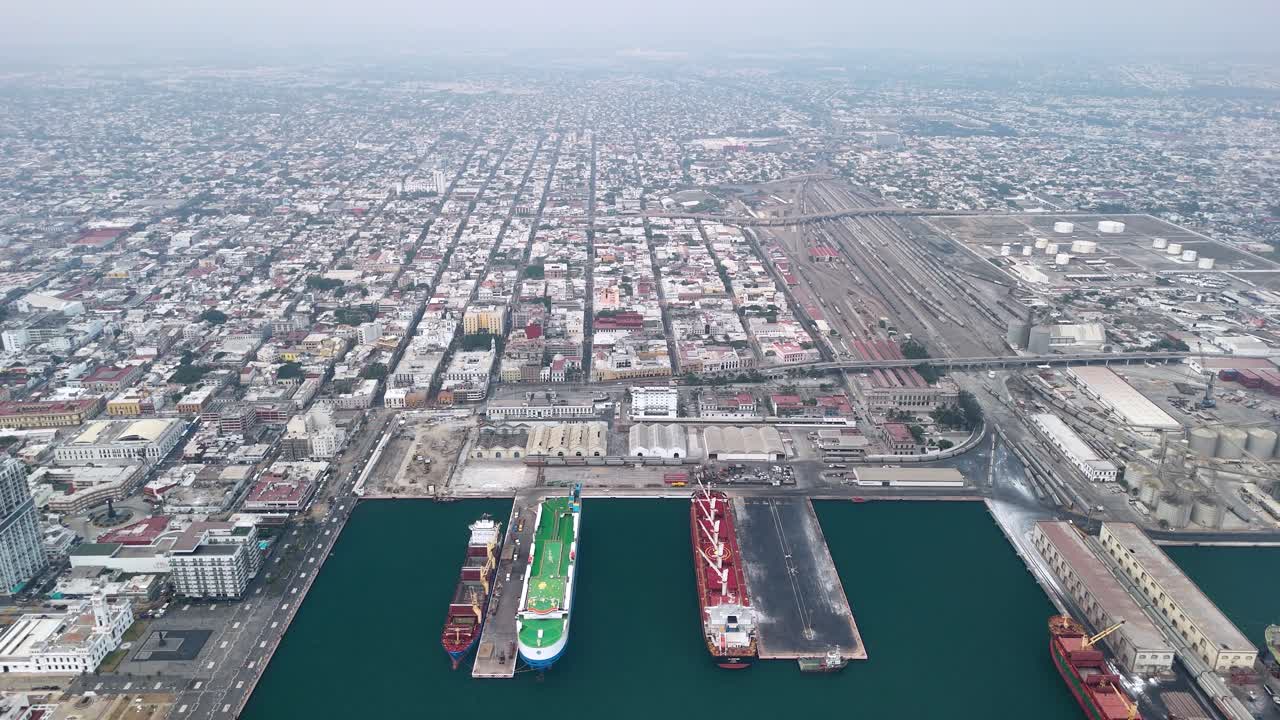 Aerial view of a large port city with cargo ships and extensive rail infrastructure