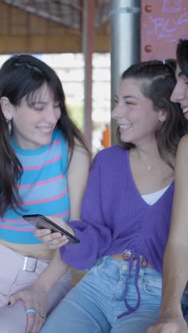 three young women friends happily looking at a smartphone together