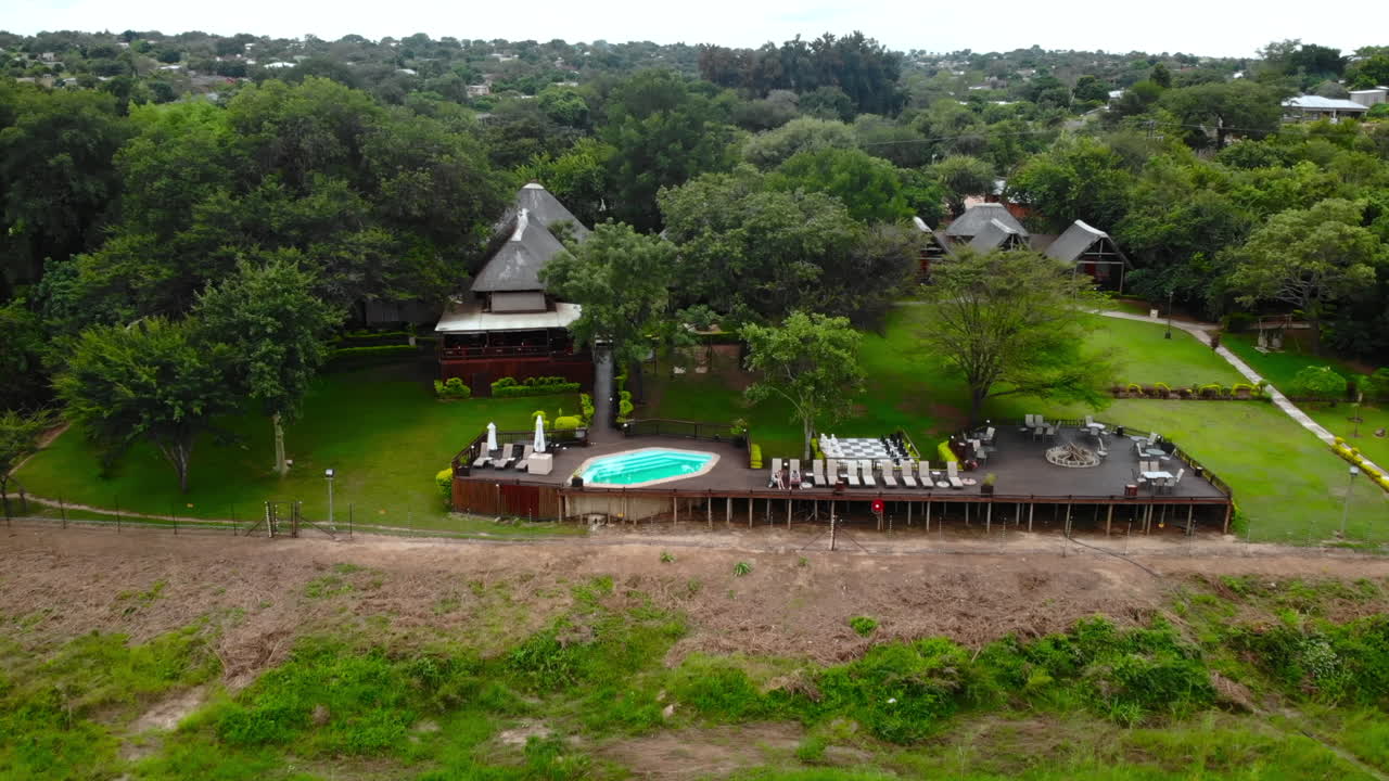 Aerial view of a beautiful lodge with a swimming pool surrounded by trees and a river
