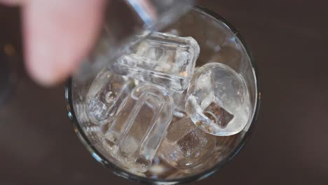 Pouring-vodka-into-shaker-glass-filled-with-ice-cubes,-making-espresso-martini