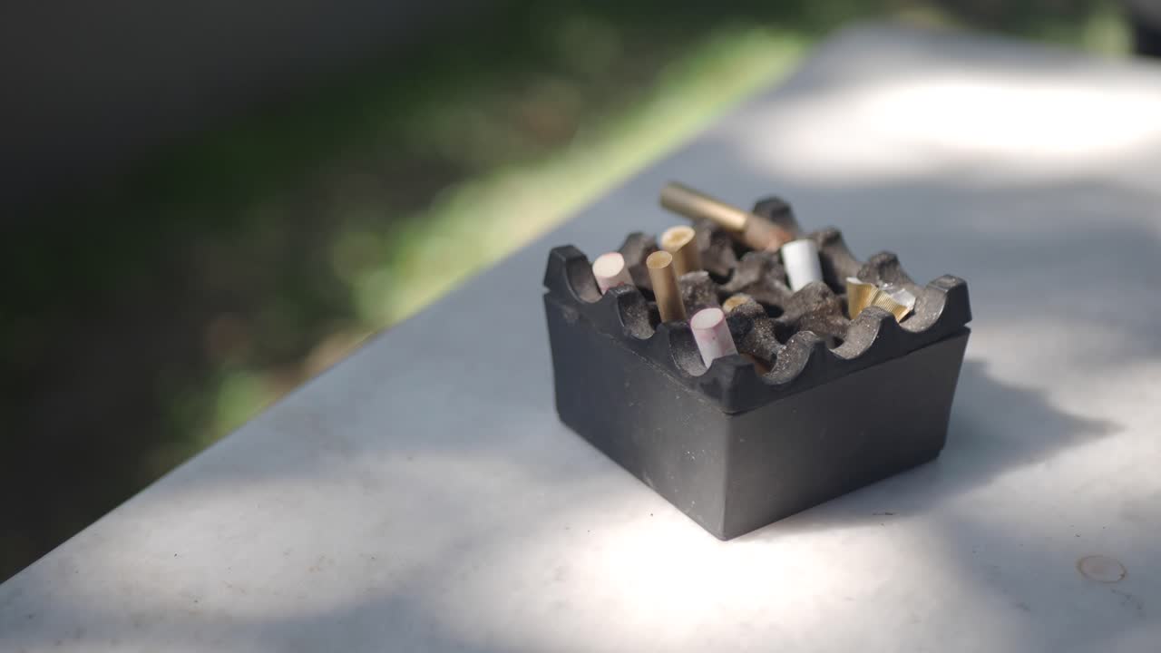 Used ashtray with cigarette butts on a table.