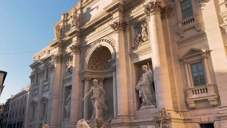 a sunlight striking at the baroque exterior of trevi fountain in rome, italy