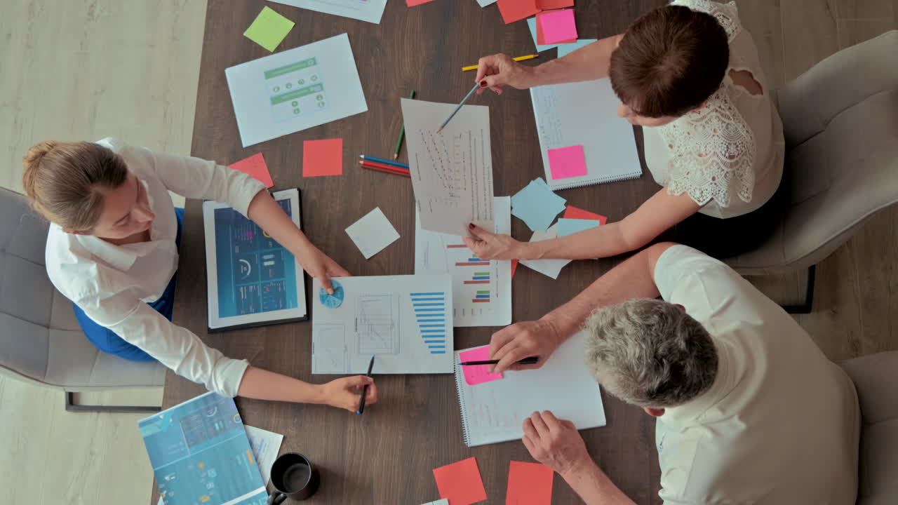 Three coworkers analysing graphs at a desk in an office