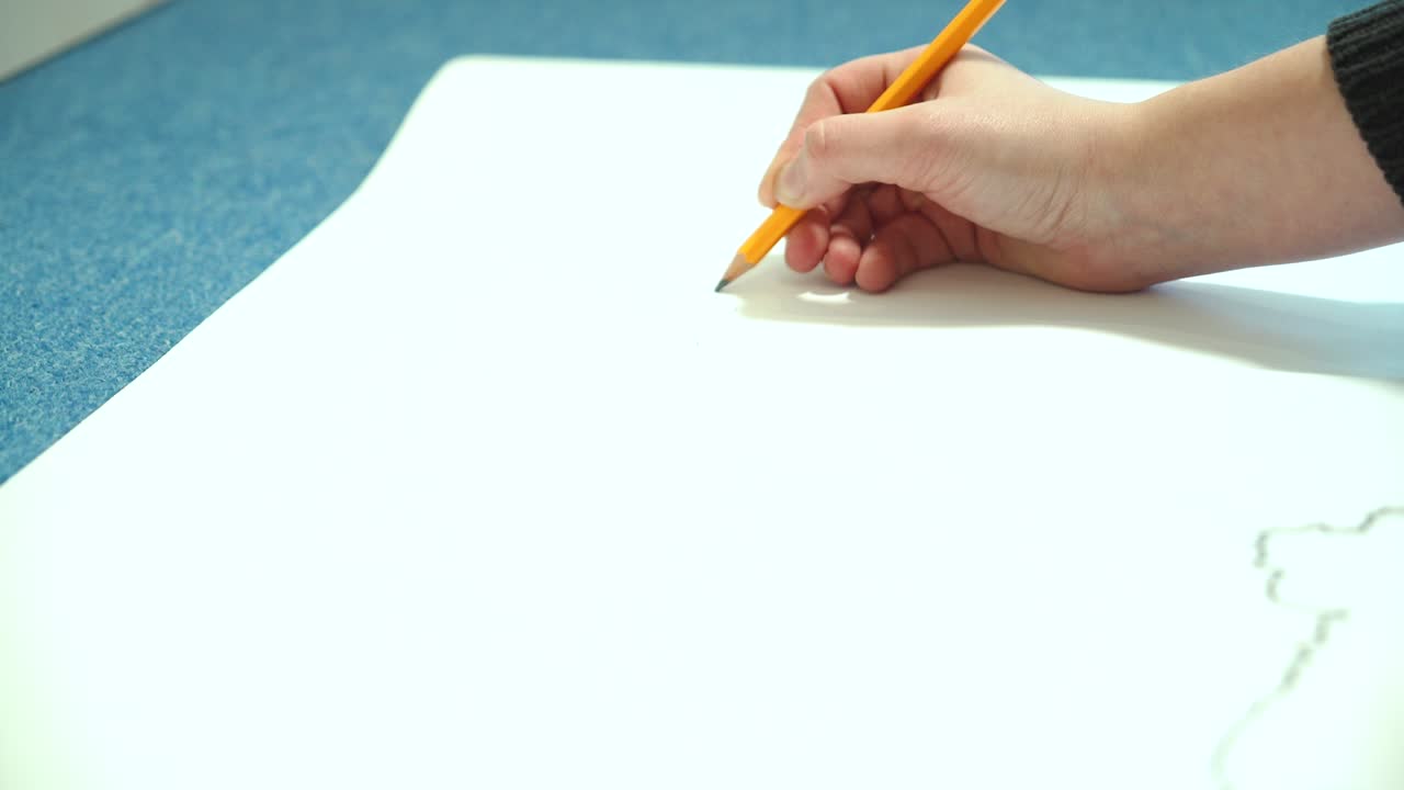 Female hand draws with a pencil. Young woman learns to draw.