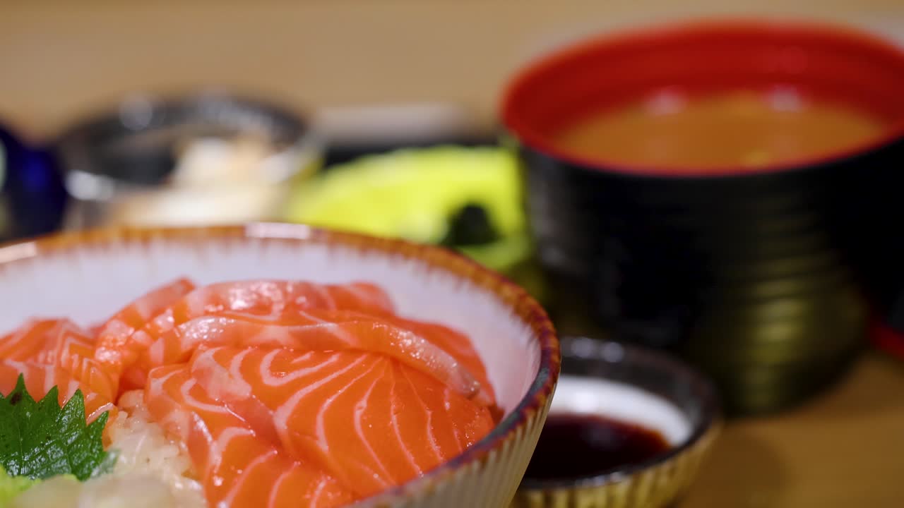 Pengambilan gambar close-up yang diputar dari set makanan donburi salmon Jepang dengan sup miso dan salad