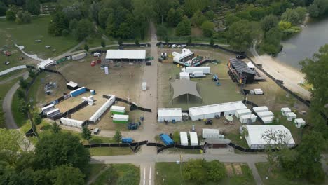 aerial view of a music festival being constructed in alphen aan den rijn, with stages, tents, trucks, and lake surroundings