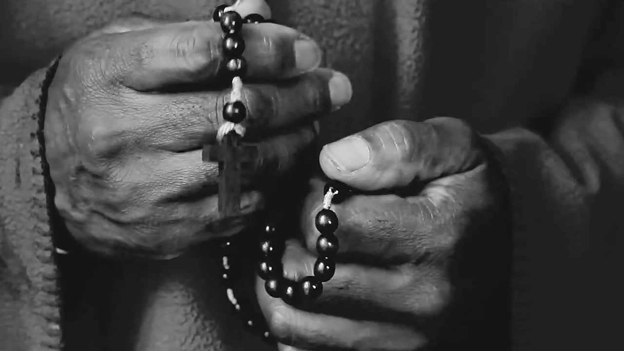 praying to God with hand's together with cross on table with people and black background stock video stock footage