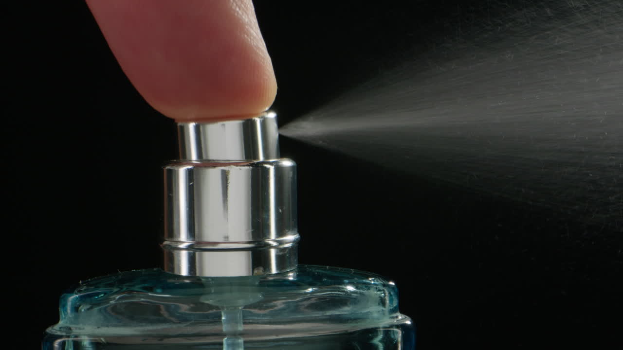 Young man applying perfume to skin in the dark, close up of spraying deodorant luxury perfume.