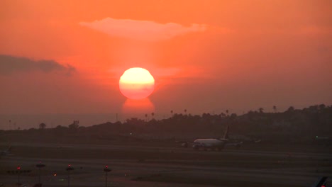 a plane arrives at an airport at sunset or sunrise