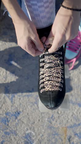 person lacing up roller skates with leopard print laces