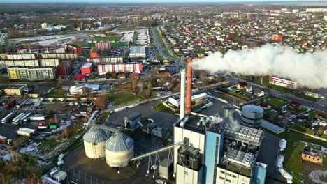 Fábrica-Local-Que-Emite-Humo-Cerca-De-Un-Pequeño-Municipio,-Vista-Aérea-De-La-órbita