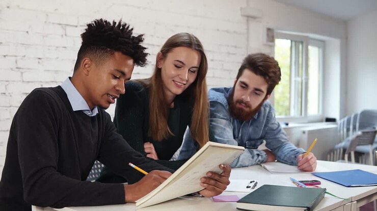 multi ethnic group of people working together. Young african guy explaining something to his colleagues pointing to notebook