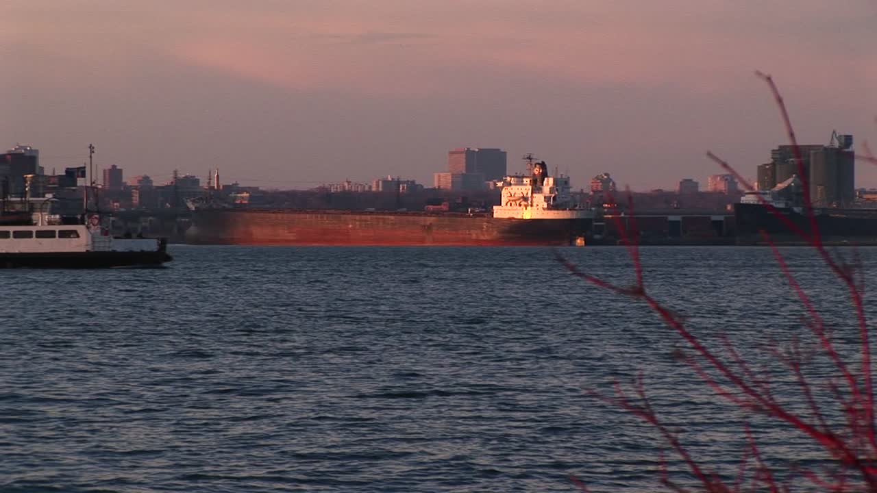 un barco de pasajeros canadiense pasa junto a un carguero del lago en el lago ontario