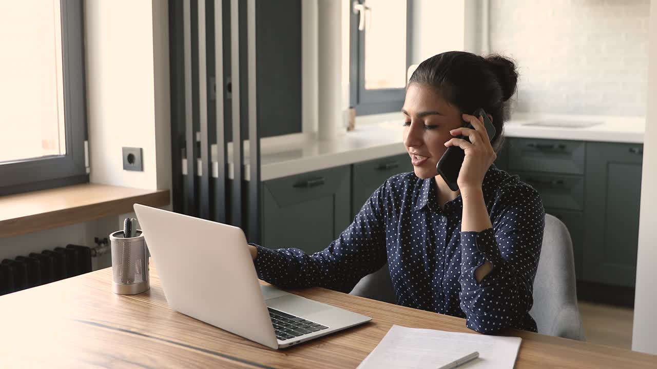 una mujer de negocios india tiene una agradable conversación formal por teléfono móvil.