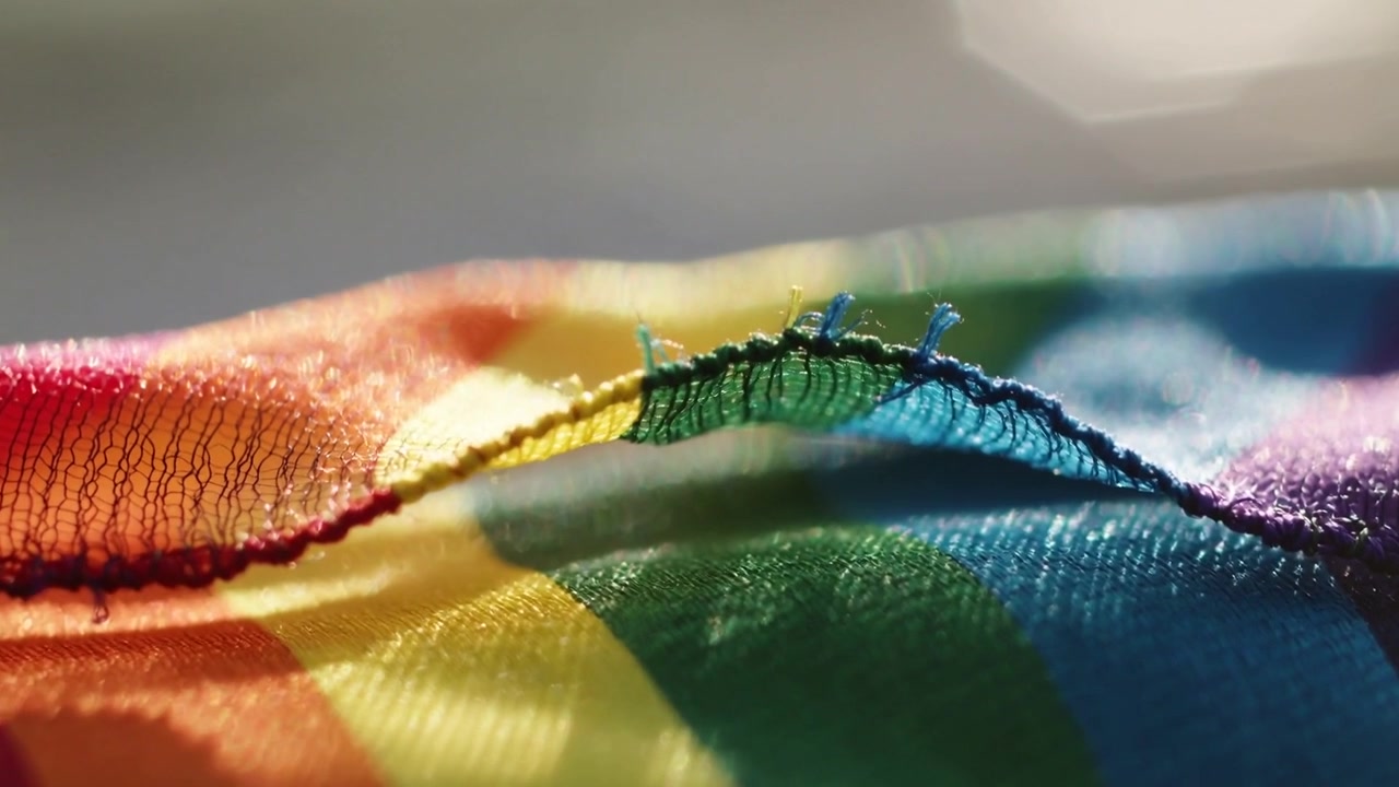 La messa a fuoco della fotocamera rivela un tessuto a strisce arcobaleno in studio, mostrando l'orlo sfilacciato e bande accattivanti.