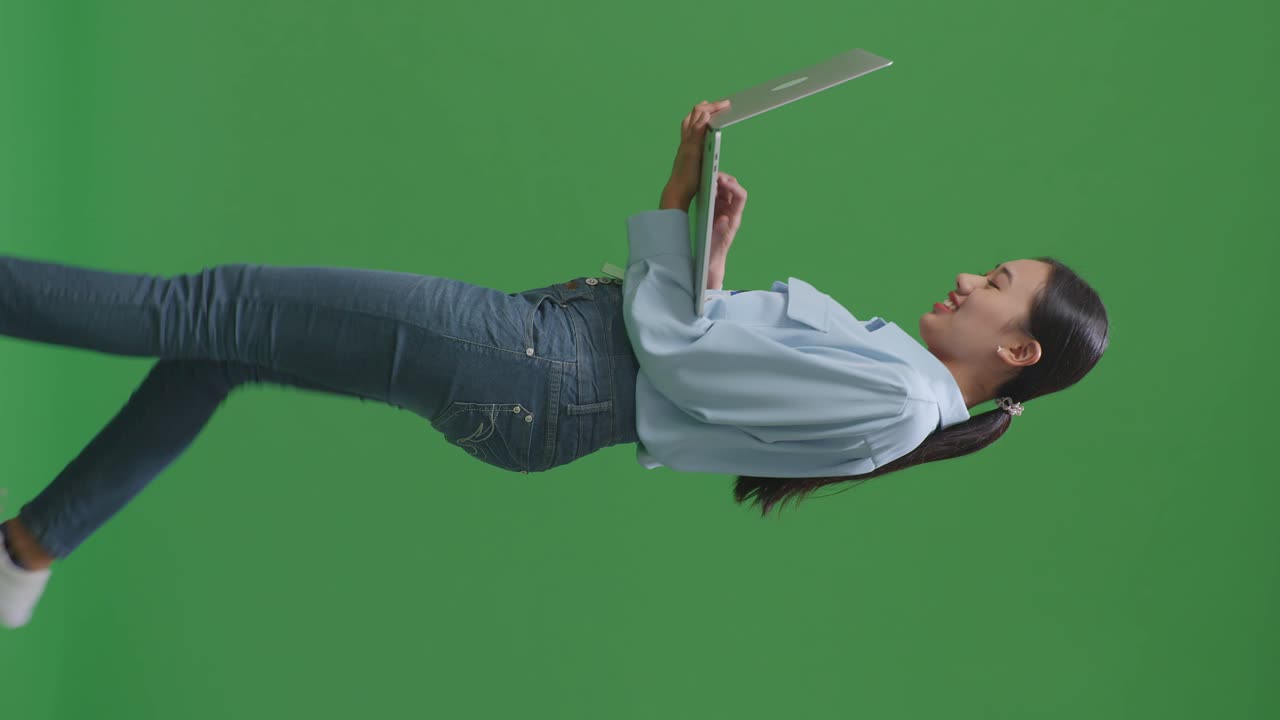 스튜디오에서 녹색 화면 배경에서 는 동안 노트북 컴퓨터를 사용하는 아시아 사업가의 측면 시각