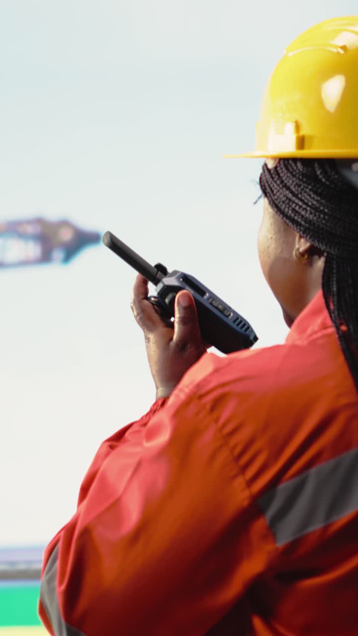 Vertical video Offshore platform worker speaking in walkie talkie, testing safety system