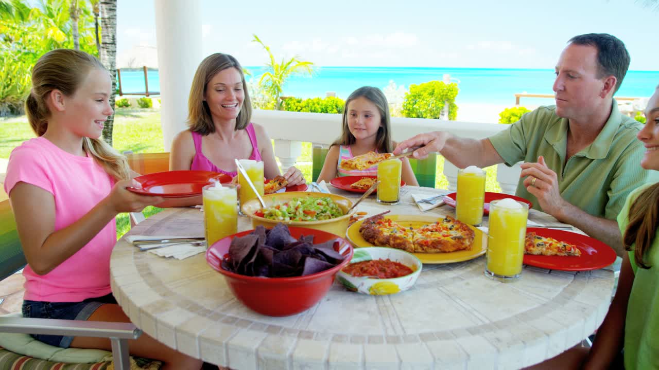 Caucasian parents daughters eating lunch in beach resort