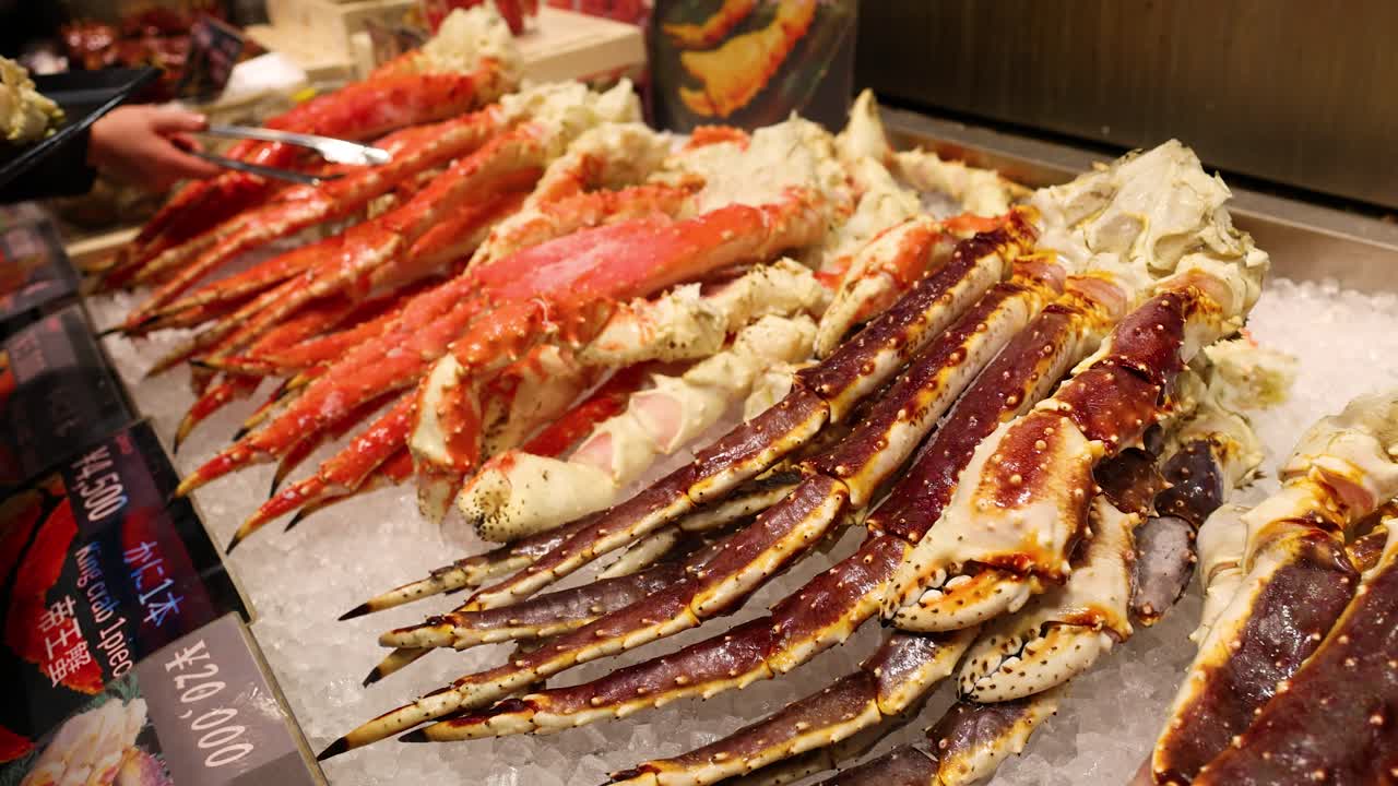Close-up shot of red king crab legs displayed on crushed ice at a seafood market