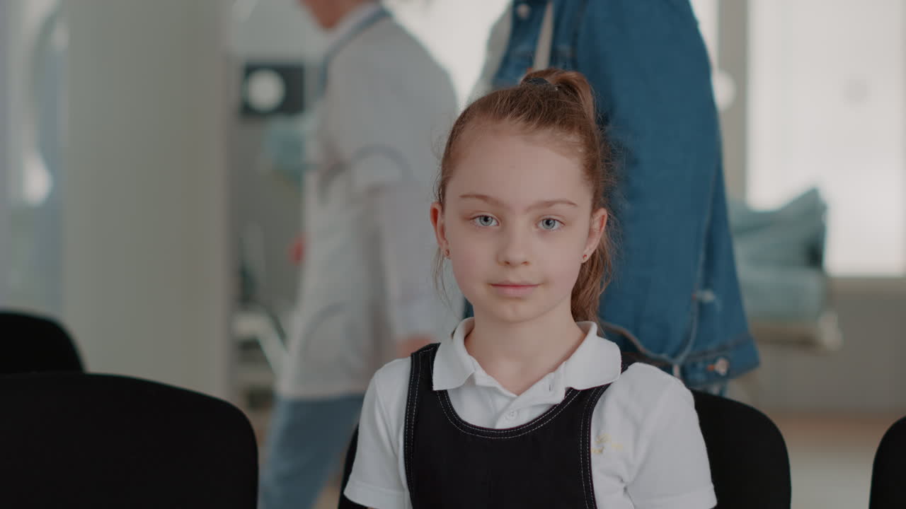 Portrait of young girl sitting on chair in waiting room area