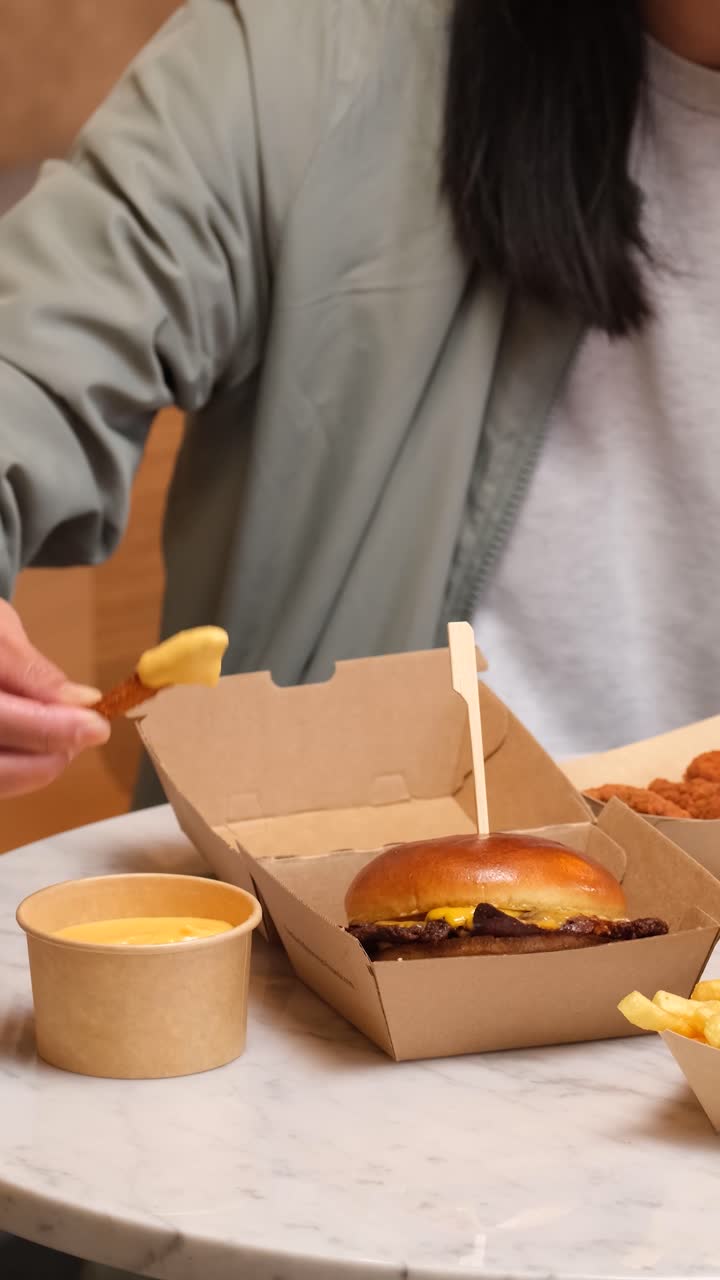 Vídeo vertical de batatas fritas de batata doce mergulhadas em molho de queijo cremoso com uma refeição de hambúrguer ao lado