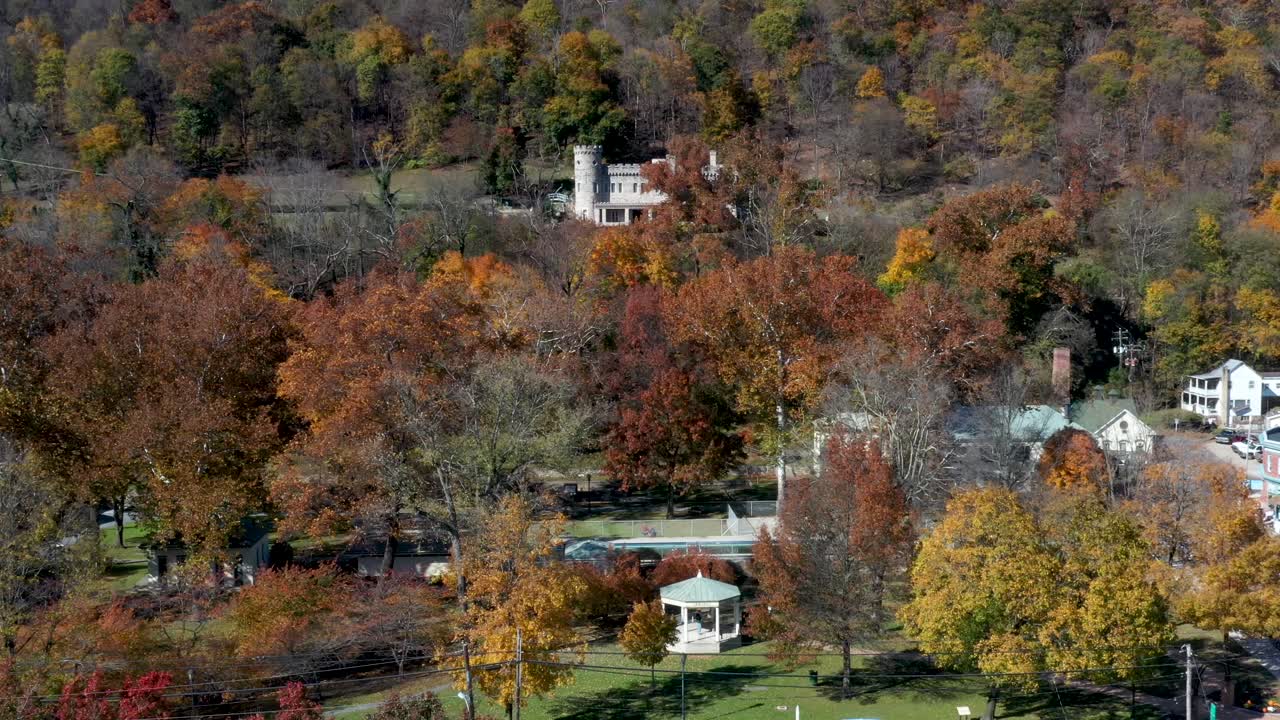 la plataforma rodante aérea pasa por el parque estatal de berkeley springs y muestra el castillo en la colina de arriba, los baños romanos, la glorieta y los colores otoñales