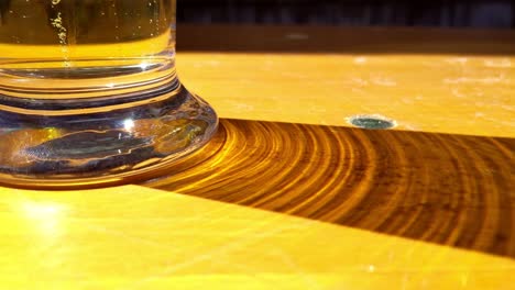 glass of carbonated beer casting shadow on wooden table