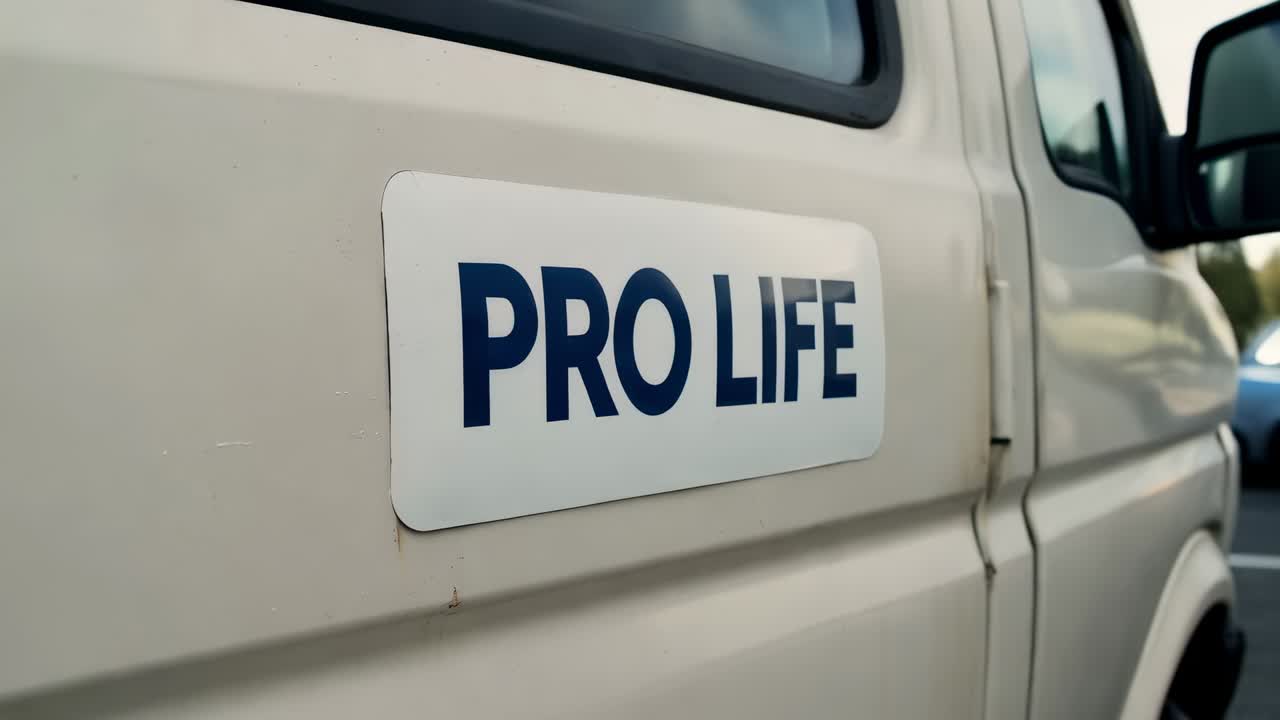 Zoom della camera, operatore che si avvicina alla porta del furgone sulla strada ed evidenzia lo sticker PRO LIFE