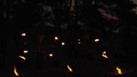 fire jugglers in a dark forest