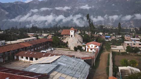 Ziehen-Sie-Die-Drohnenaufnahme-Einer-Kirche-Auf-Einem-Felsen-Weg,-Die-Sich-In-Einer-Kleinen-Stadt-Im-Hochland-Von-Peru-Befindet