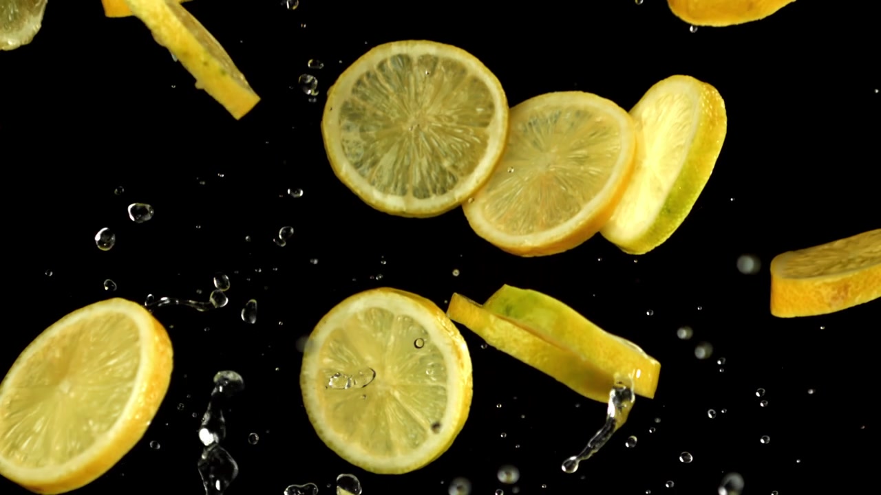 Fette di limone fresche e gocce d'acqua che cadono al rallentatore