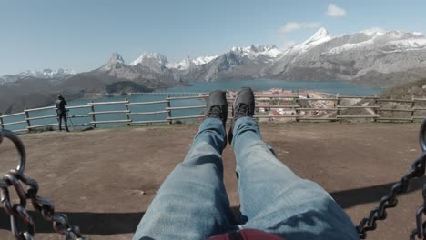 pov using swing in front if snowy mountain peaks un riaño, león, spain on a beautiful winter sunset