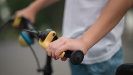 close-up of a young boy s hand gripping the brake lever on a bicycle s handlebar