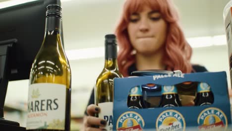 a lively atmosphere is created as a young woman checks out diverse local wines and craft beers at a convenience store during the afternoon. customers appreciate the variety.