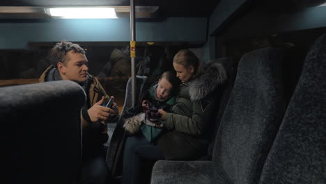 mom dad and son traveling bus in the evening and using cellphones