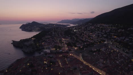 Dusk-aerial-view-of-Dubrovnik,-Croatia-with-cliffs-and-city-lights