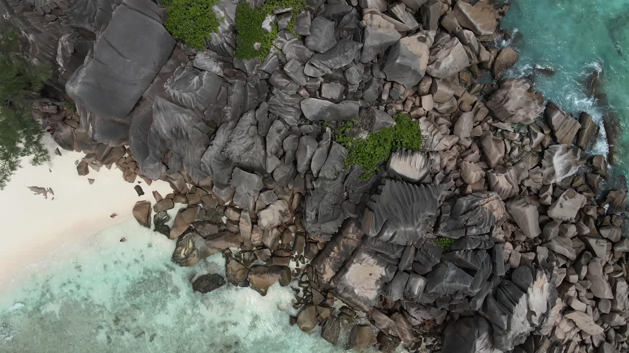 Pemandangan di pulau La Digue di Seychelles direkam dengan drone dari atas menampilkan samudra, bebatuan, dan pohon kelapa.