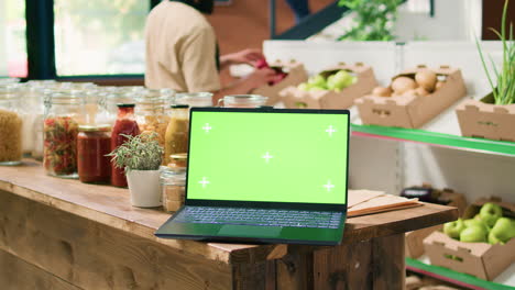 portátil de pantalla verde en la tienda ecológica local