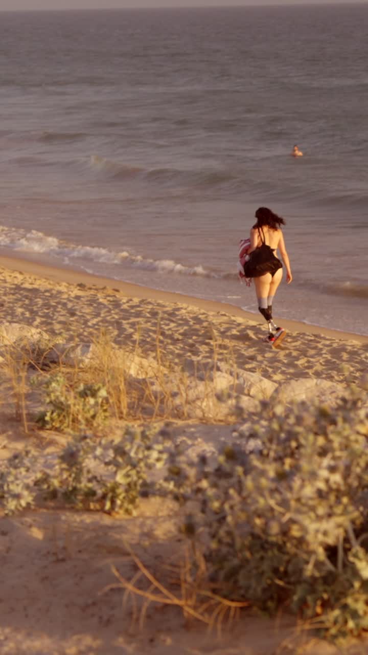 Woman with Prosthetic Legs Walking on the Beach at Sunset