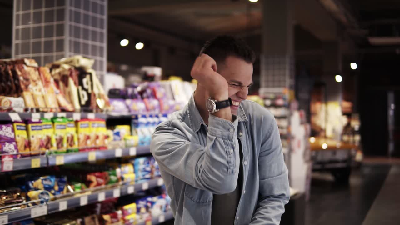 슈퍼마켓에서 쇼핑 트롤리와 함께 춤을 추는 남자. 비어있는 식품 가게에서 긍정적인 춤