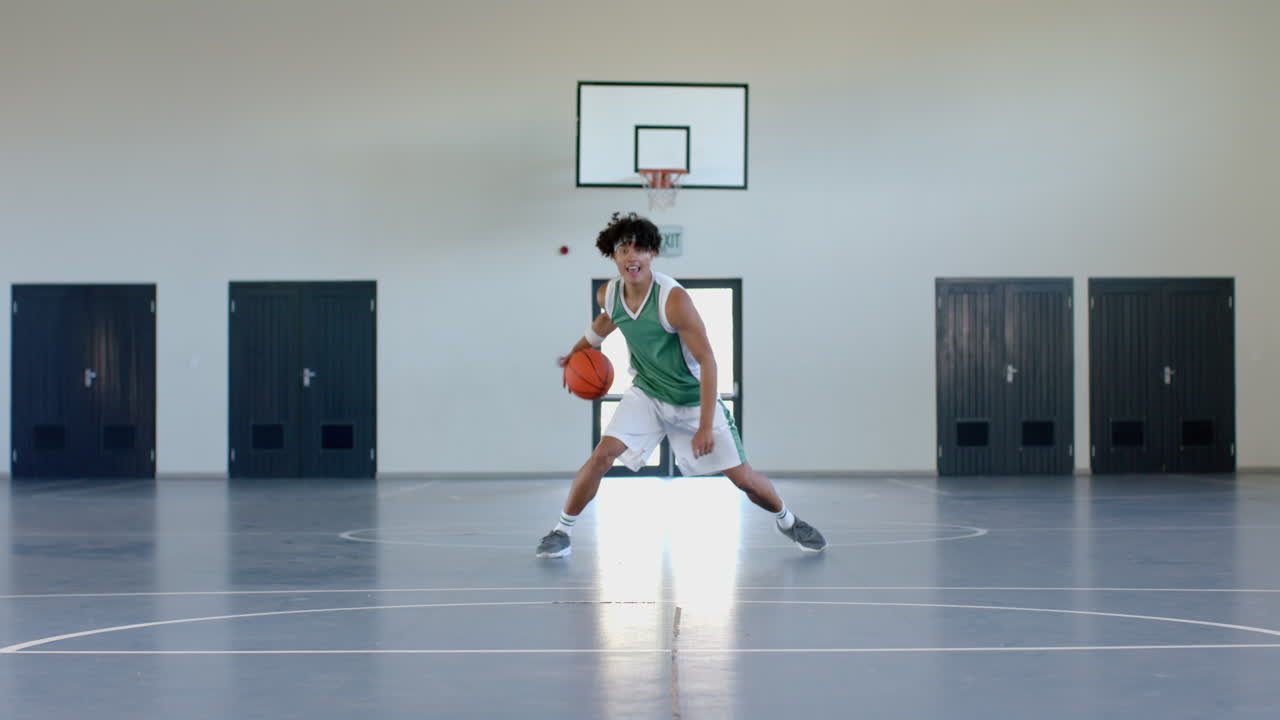 joven biracial juega al baloncesto en una cancha cubierta