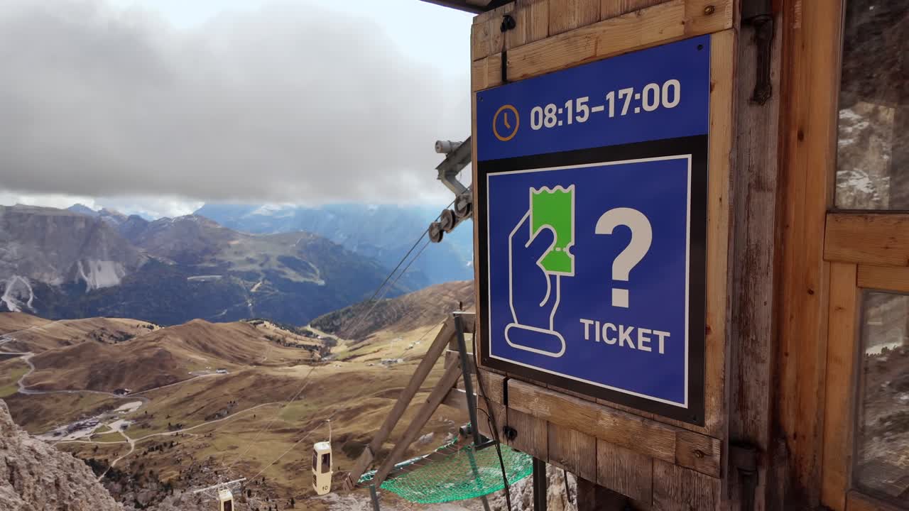 Cable car ticket booth perched on a high-altitude station in the Dolomites. Offers stunning views of Langkofel, Plattkofel, and rolling mountain slopes, perfect for alpine adventures and hiking.